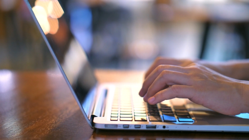 Hands typing on a laptop keyboard during computational work