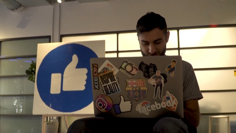 Hombre con laptop de Facebook frente al ícono de “me gusta”