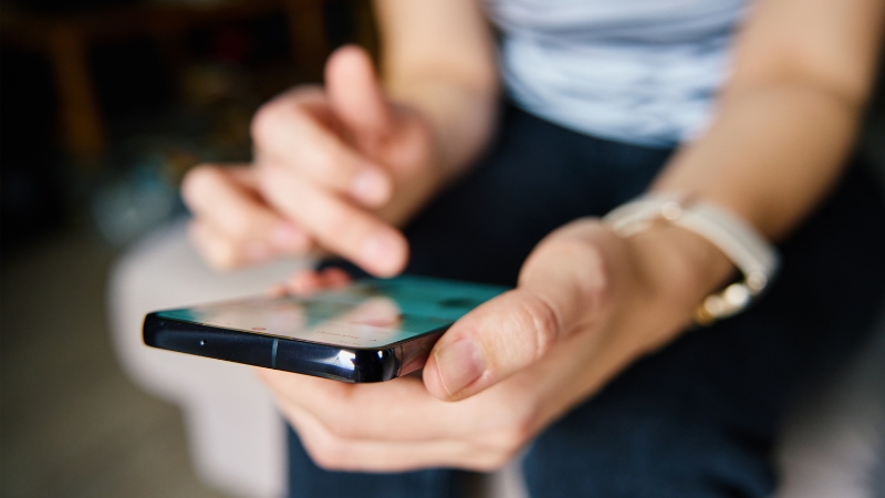 Persona utilizando un teléfono móvil, enfocada en la pantalla