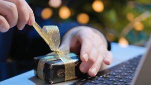 Person opening a small wrapped box at a laptop as part of corporate gift ideas for clients and business partners