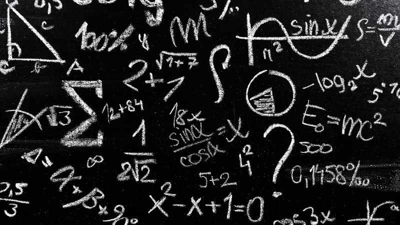 A chalkboard filled with math symbols and equations drawn in white chalk
