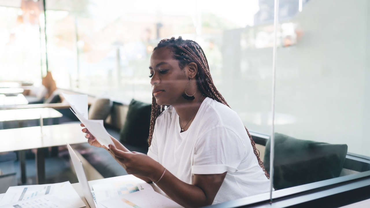 A woman reviews paperwork inside a quiet glass office space