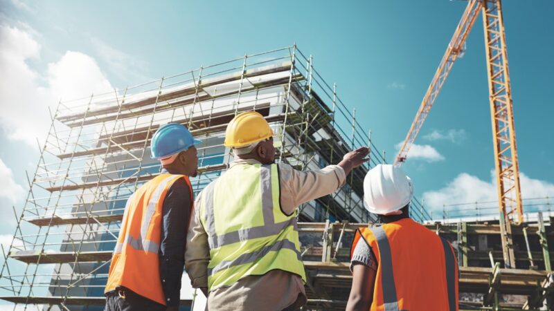 Construction workers review a building site before permit approval and project work begins