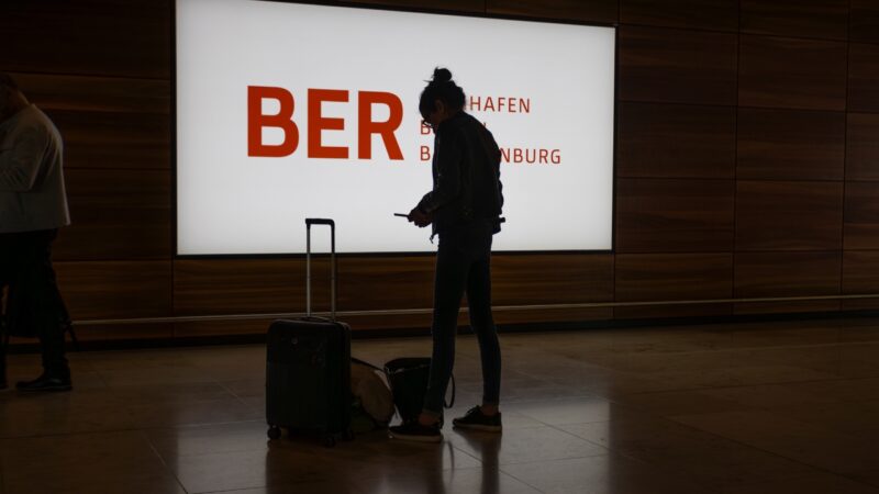 Traveler waits with luggage at Berlin Brandenburg Airport