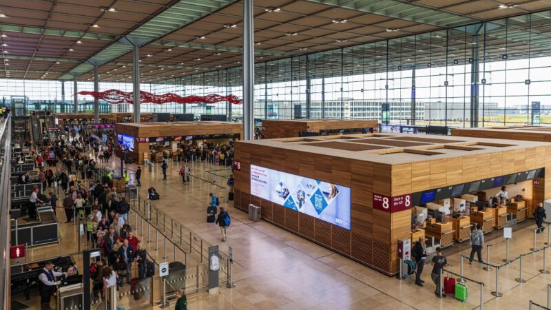 Passengers queue at check-in counters inside Berlin Brandenburg Airport