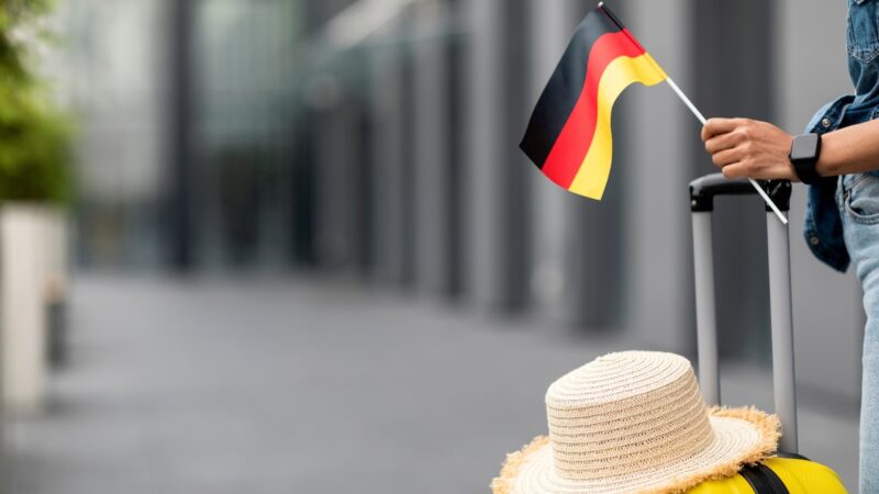 Traveler holds a German flag beside luggage before a trip to Germany